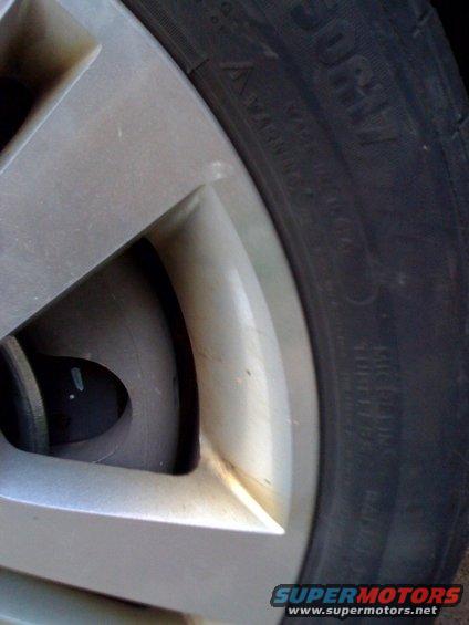 Close-up of a car's wheel and tire. Text on the tire is visible