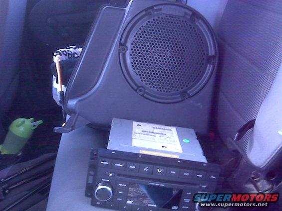 Car stereo and a speaker enclosure sitting on a car seat