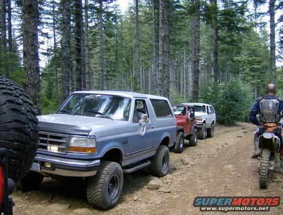 Blue and silver 1996 Ford Bronco on dirt road, three-quarter front view