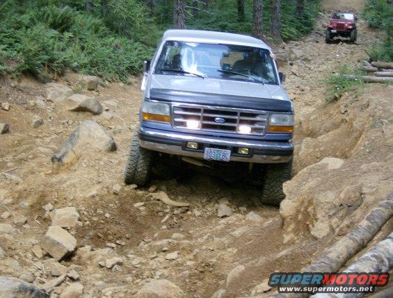 Silver Ford Bronco navigating a rocky, wooded trail