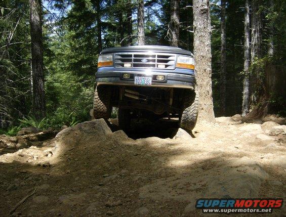 1996 Ford Bronco front view, tires on rocks, forest trail