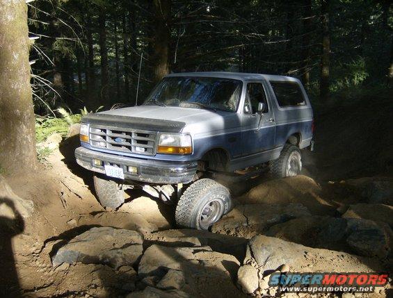 1996 Ford Bronco navigating a difficult rocky off-road path in a forest