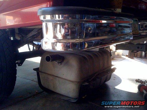 Fuel tank installed beneath a red vehicle's rear bumper