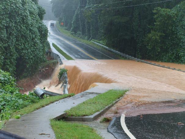 Car driving on flooded road with water spilling over the side