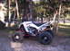 2009 Yamaha RAPTOR 660 - A white Yamaha ATV with red accents is parked on a gravel surface surrounded by trees.