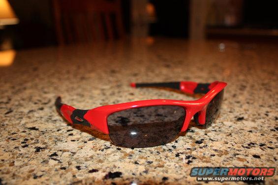 Red Oakley sunglasses with black accents on a speckled countertop