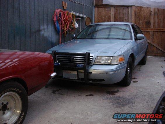Light blue 2002 Ford Crown Victoria with push bar parked next to a red car
