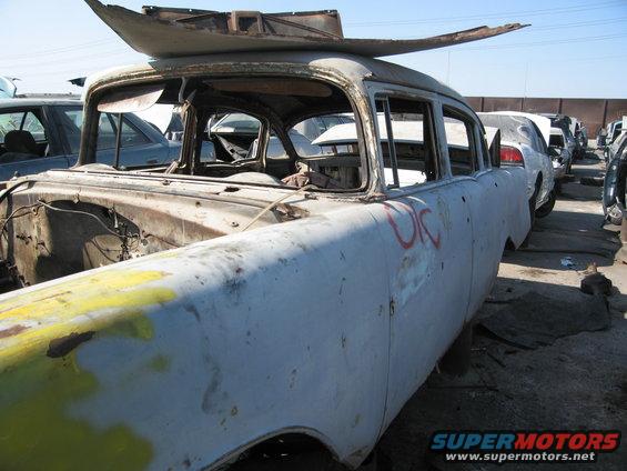1955 Chevrolet sedan body, stripped and rusted, in junkyard. Another car is visible behind it