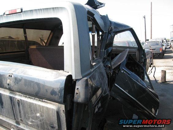 Damaged dark SUV, 3/4 front view. Visible interior and rear