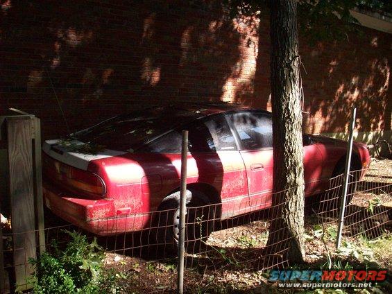 1992 Nissan 240SX coupe parked outdoors, partially obscured by a tree and fence