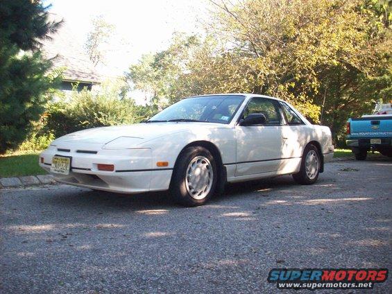 White coupe with pop-up headlights parked on asphalt, front-left view