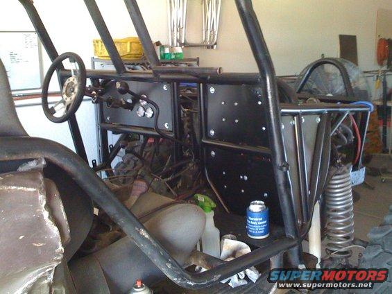 Custom buggy interior with roll cage, steering wheel, and dashboard. A can of spray paint sits on the floor