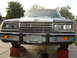 1984 Ford LTD - Front view of a brown Ford car with a chrome grille and dual headlights, raised on red jack stands.