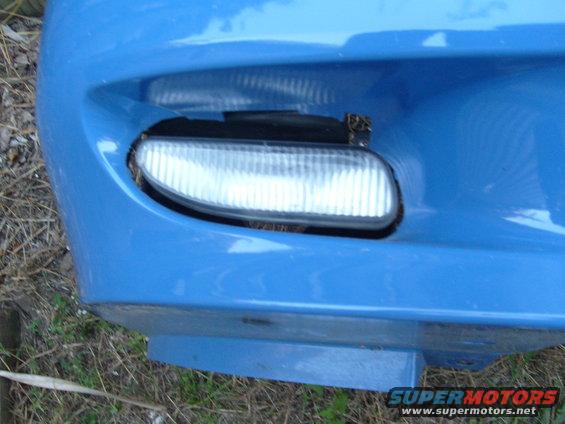 blue car bumper with fog light, some grass and dirt visible
