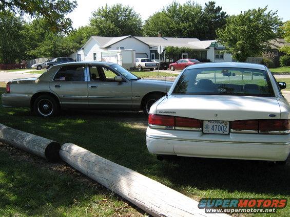 White sedan's rear view, showing Kansas license plate 47002 and 'Grand Marquis' badging