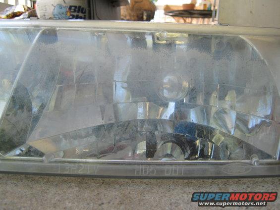 Close-up of a dusty car headlight assembly with visible text 'HBS DOT'