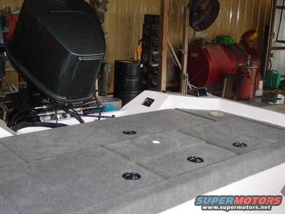 boat motor and gray carpeted deck with storage compartments