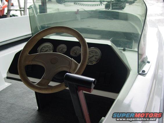 Boat interior showing steering wheel, throttle, and dashboard gauges. Supermotors.net logo visible