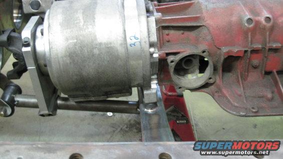 Close-up of a silver transmission housing with blue marker '32' next to a red component, with metal framing