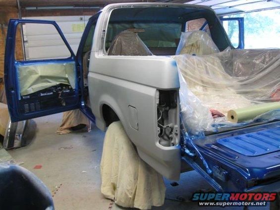 1992 Ford Bronco with doors open, covered in plastic and primer for bodywork