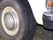 1979 Ford F-250 - A close-up view of a tire and hubcap on a white vehicle, showing part of the fender and bumper.