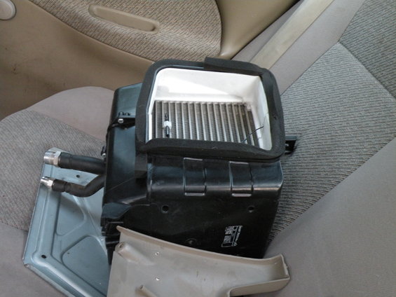 heater core assembly with hoses and fins, sitting on car seats