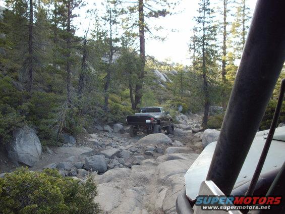 Truck driving on a rocky mountain trail. Another vehicle is in the foreground