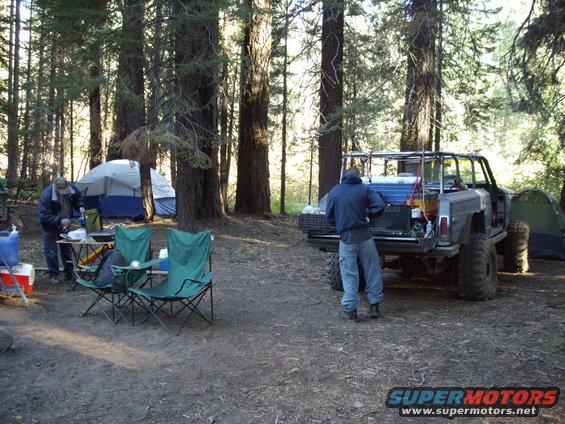 Modified SUV with large tires parked in a forest campsite