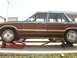 1984 Ford LTD - A brown station wagon with wood paneling is elevated on red ramps and a jack.