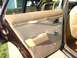 1984 Ford LTD - The interior door panel of a car features tan fabric and vinyl trim with chrome accents.