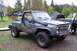 1988 Chevrolet Blazer - This heavily modified pickup truck features a snorkel and is parked next to another vehicle in a yard.