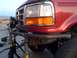 1989 Ford Bronco - Front end of a red 1989 Ford Bronco, modified with a custom bumper and supported by jack stands.