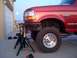 1989 Ford Bronco - This red Ford Bronco is elevated on jack stands for maintenance, with a full moon visible in the twilight sky.