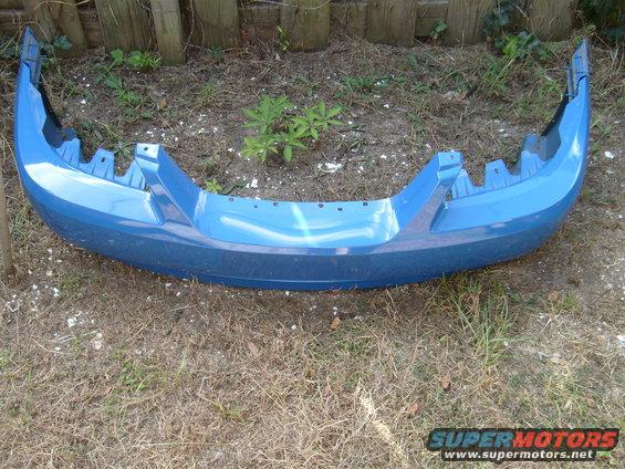 Blue car bumper with mounting brackets visible, lying on the ground