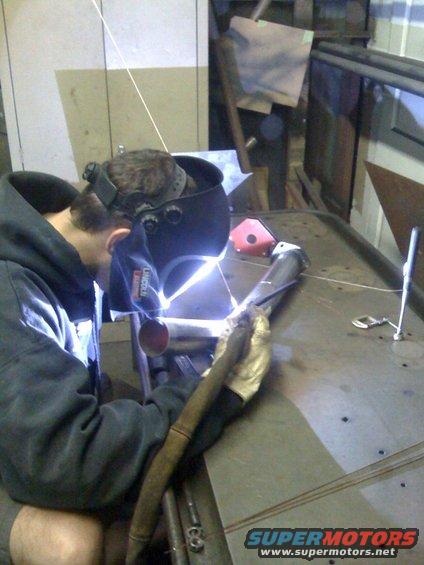 Welder working on metal pipes in a workshop