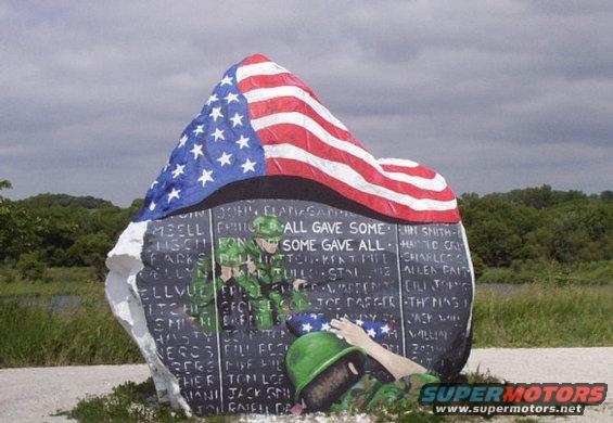 Veterans memorial stone with American flag, soldiers, and names