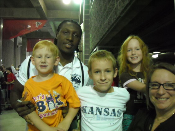 Group of people including two children and an adult woman, with a man in the background