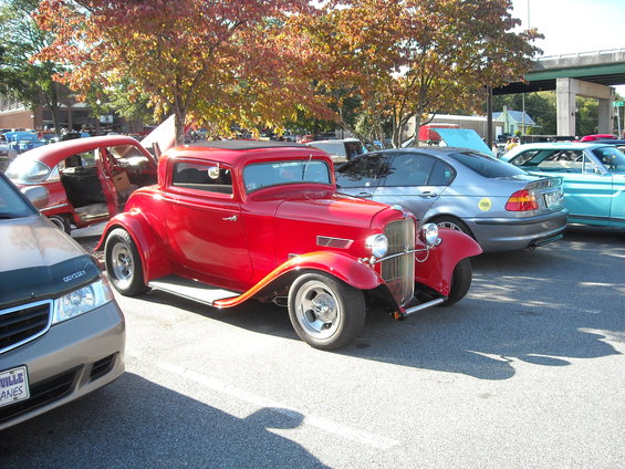 Red coupe hot rod with a black top and chrome grille, parked outdoors