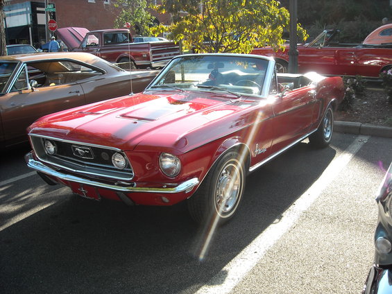 Red convertible classic car parked, with other vehicles visible