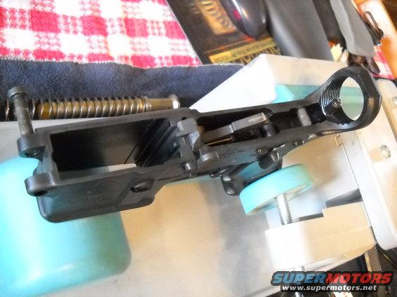 Gun receiver assembly held in a vise with a spring and bolt visible