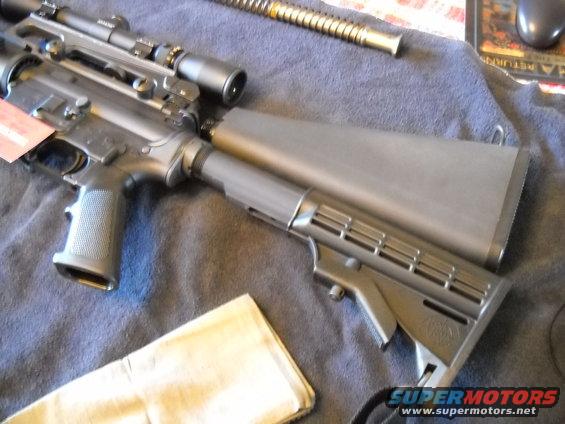 Assault rifle with scope, black, angled view, on a blue cloth