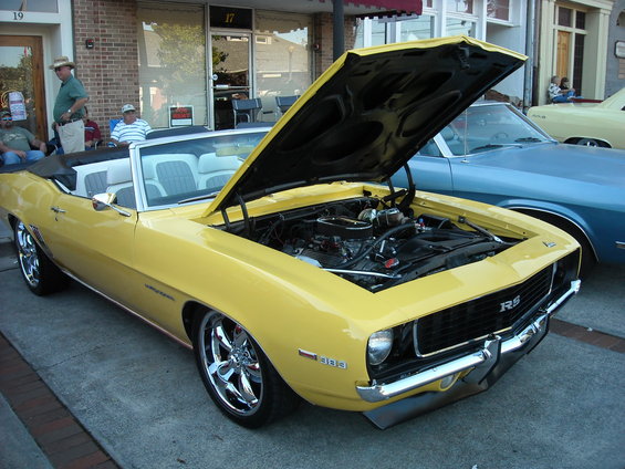Yellow 1969 Camaro RS convertible with hood open, showing engine. Chrome wheels
