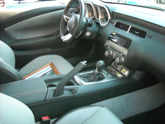 Interior view of a car, showing seats, dashboard, steering wheel, and center console with gear shifter