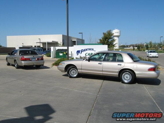 Two tan Mercury Grand Marquis sedans parked outside a building with a "PANTHER CAR" sign