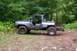 1988 Chevrolet Blazer - This modified SUV, likely from the 1980s, sits on a dirt path surrounded by trees.