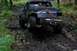 1988 Chevrolet Blazer - An off-road SUV struggles through a muddy, wooded path, its rear end visible.
