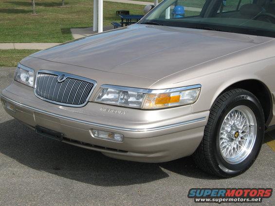 Front corner of a tan Mercury Grand Marquis with a chrome grille and wire-spoke wheels