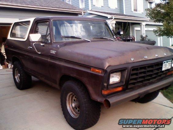 Brown 1978 Ford Bronco with a white removable top, seen from a 3/4 front angle. The vehicle has a custom metal bumper