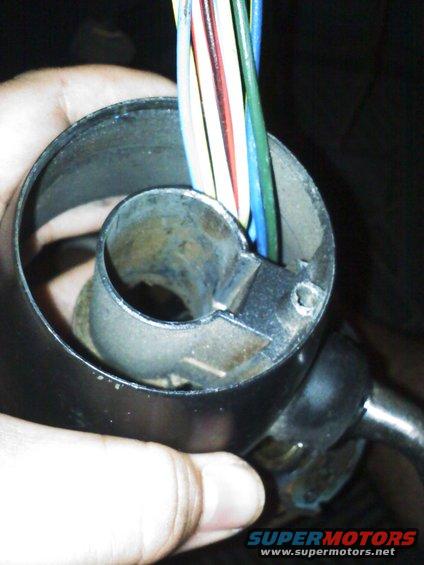 Close-up of a hand holding a steering column with a bundle of colorful wires emerging