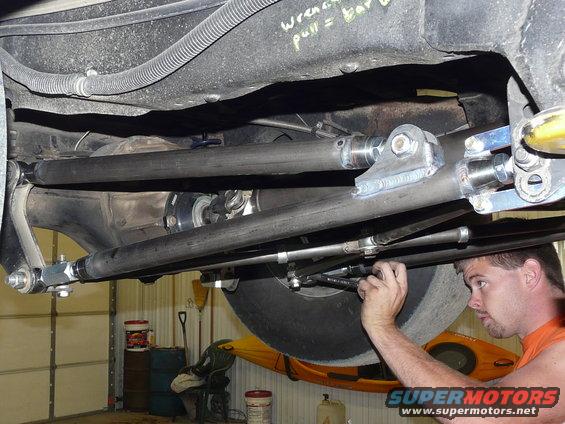 Guy working on the undercarriage of a vehicle, adjusting suspension components